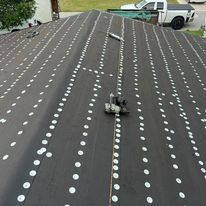 A roof with a lot of white dots on it is being installed.