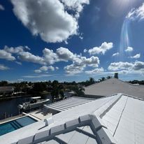 A rooftop view of a house with a pool and a blue sky with clouds.