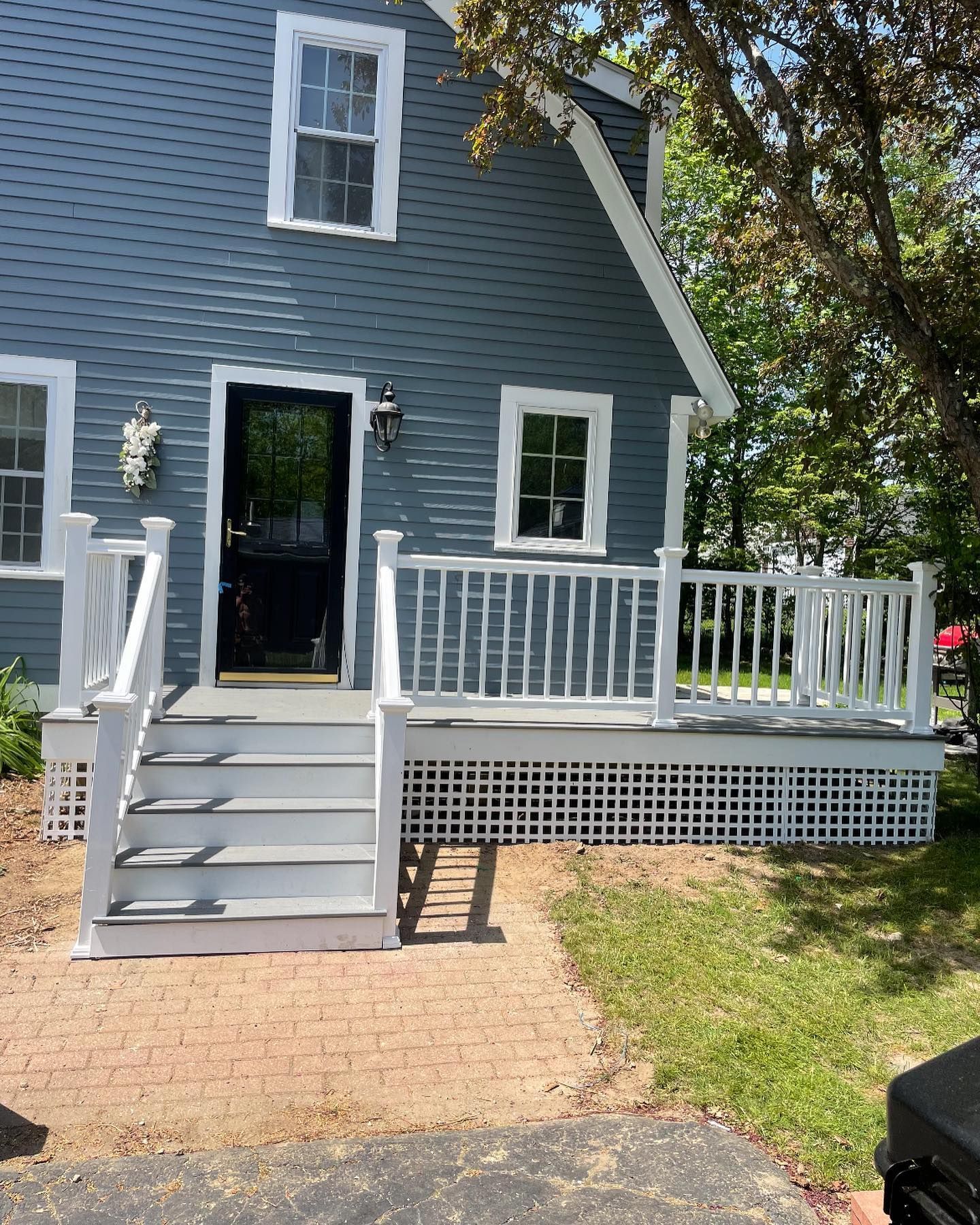 A blue house with a newly painted white front porch, white railings, and white stairs leading up to the front entrance.