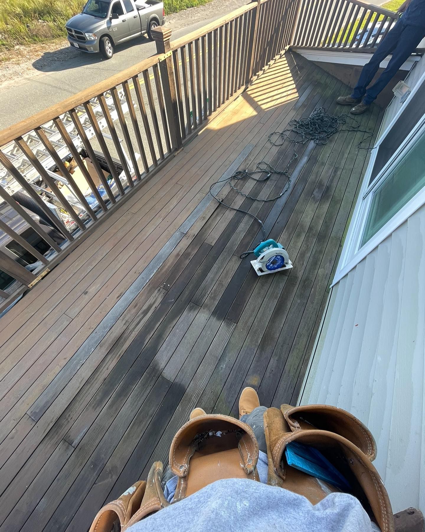 A view from a construction worker's perspective on a deck, showing a circular saw, tools, and a truck parked nearby.