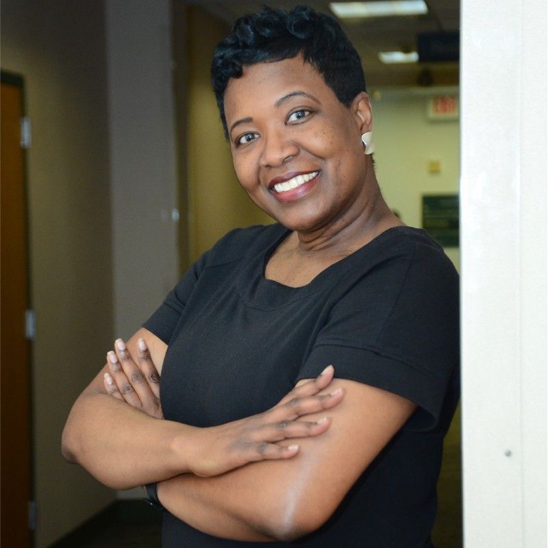 Michele Williams, a Black woman wearing a black dress,  is CFO of teh Society for Diversity
