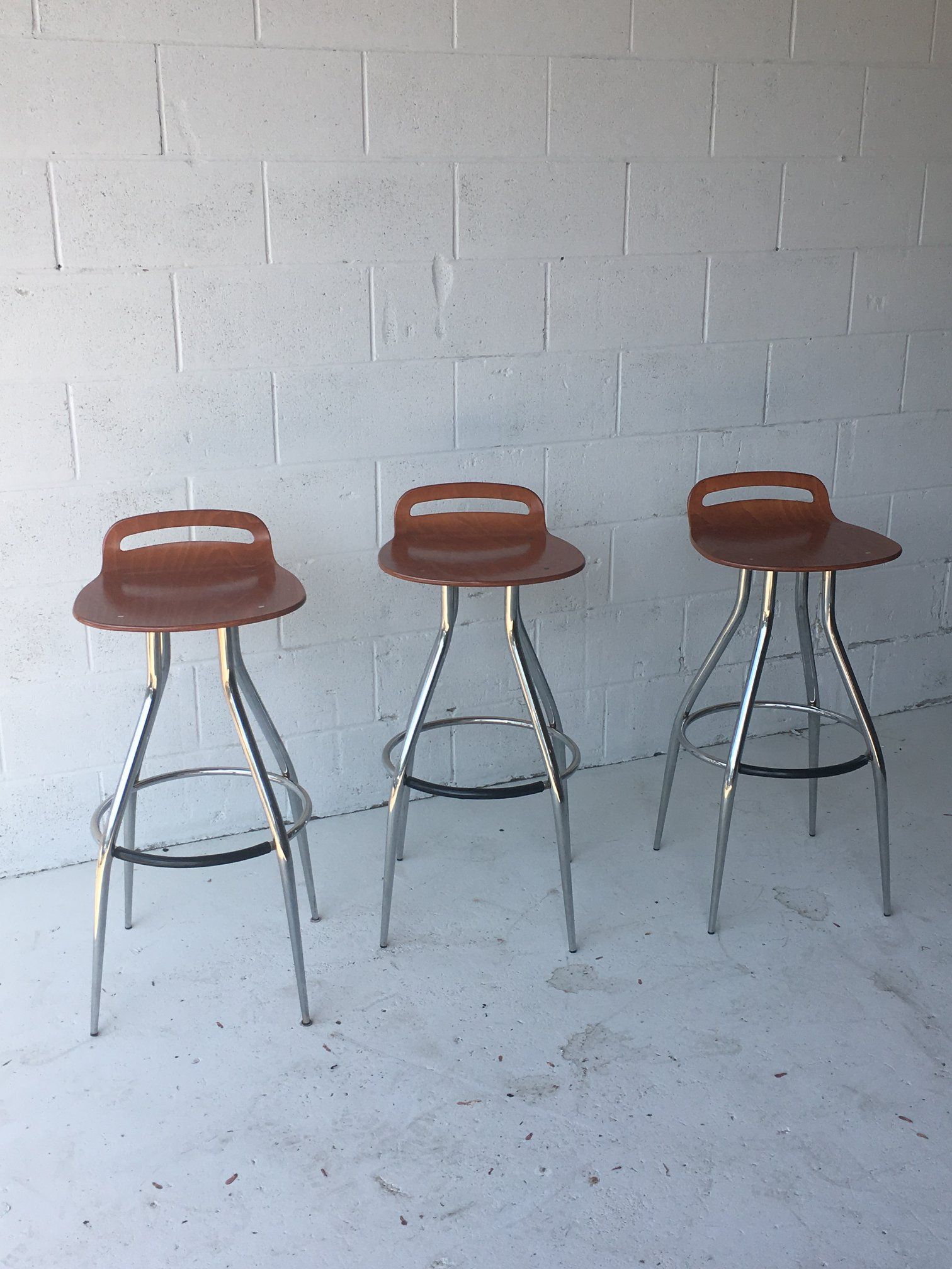 Three bar stools are sitting in front of a white brick wall.