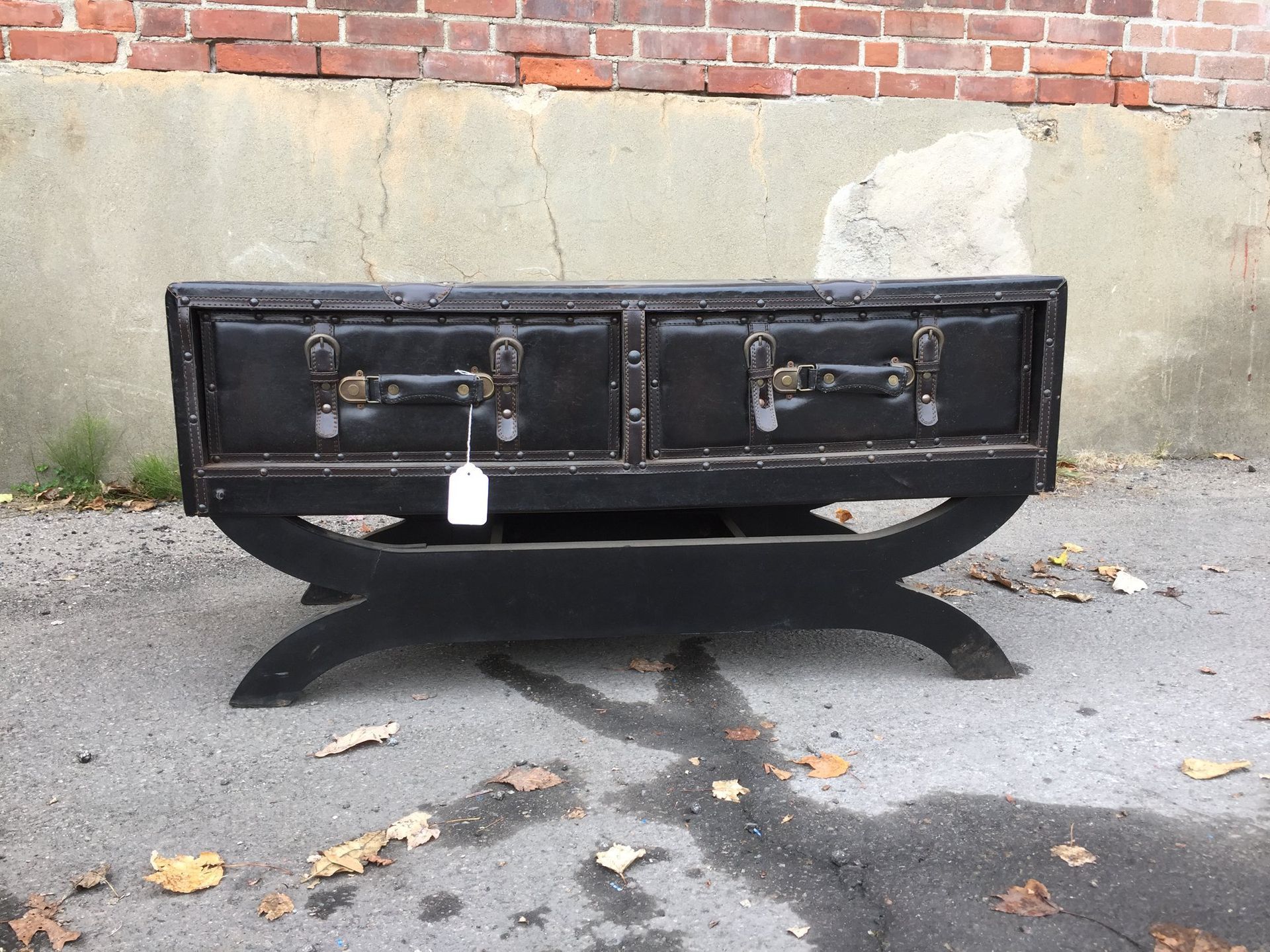A black trunk with two drawers and a tag attached to it