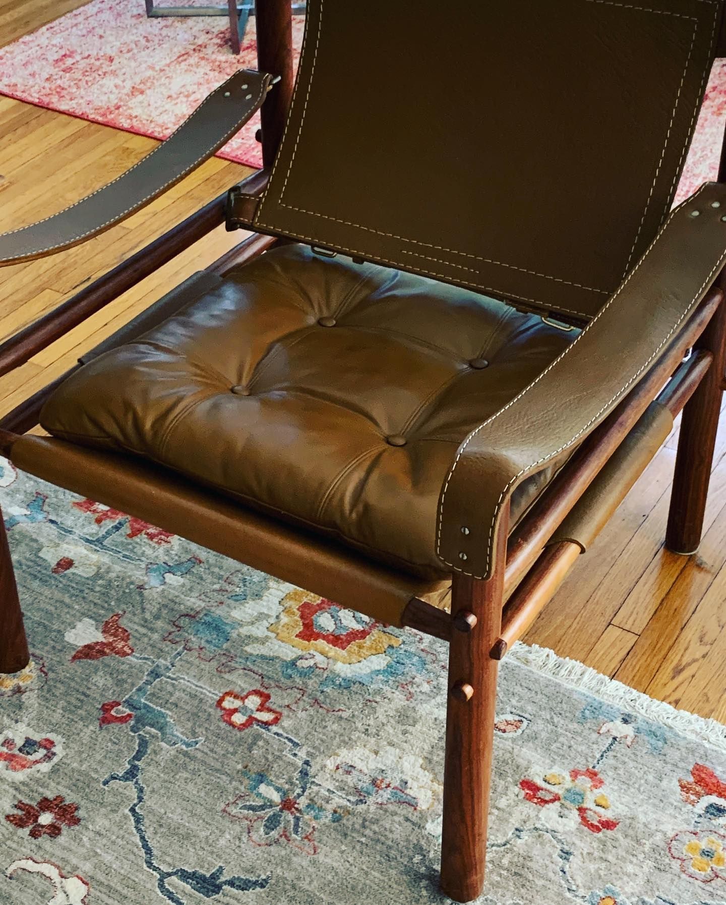 A brown leather chair with a cushion on it is sitting on a rug.