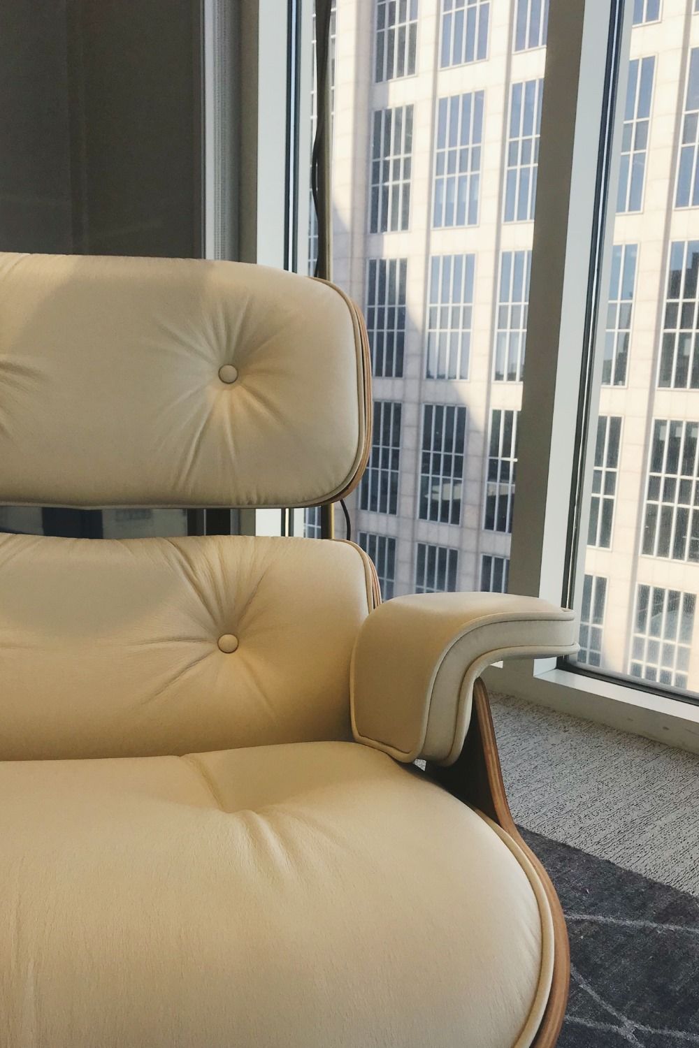 A white chair is sitting in front of a window with a building in the background