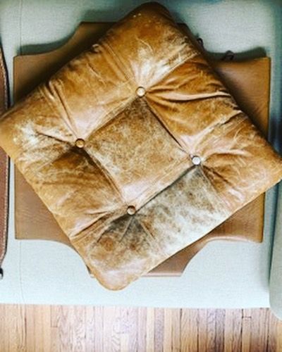 A brown leather cushion is sitting on top of a chair.