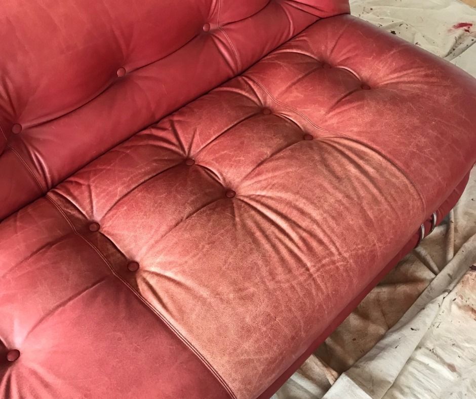 A red leather couch is sitting on a white table.