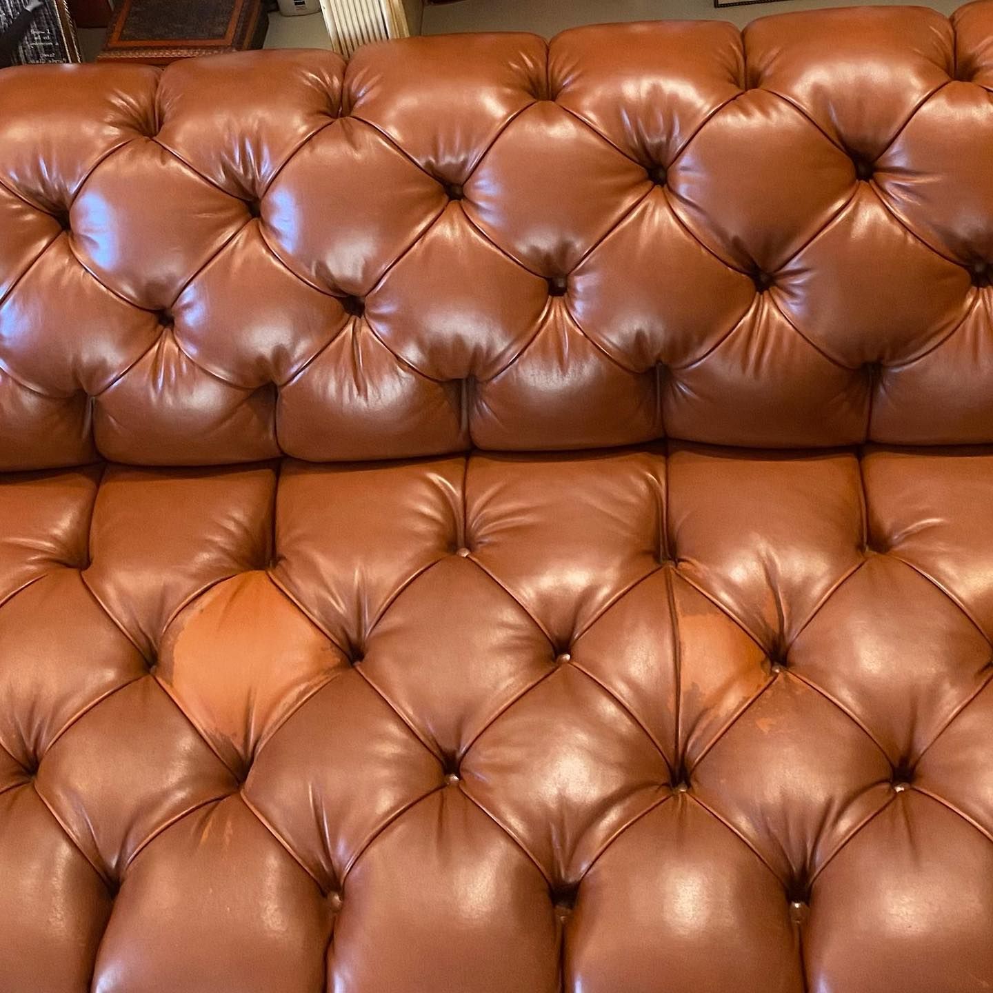 A close up of a brown leather couch with buttons on it.