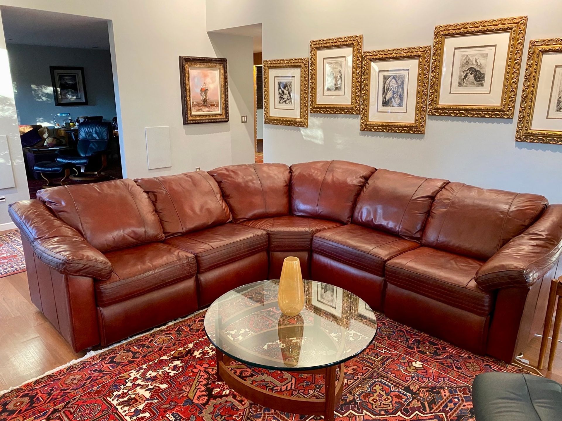 A living room with a large leather sectional couch and a glass coffee table.