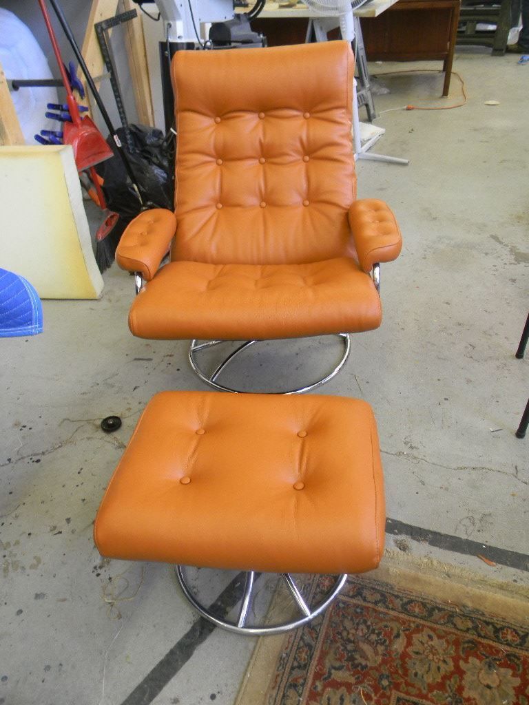 An orange leather chair and ottoman are in a room
