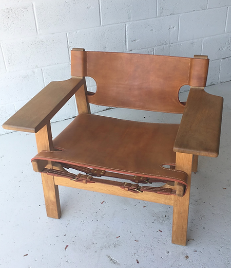 A wooden chair with a brown leather seat and back