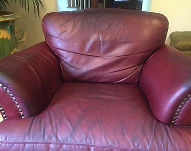 A red leather chair with studs on the arm rests is sitting in a living room.