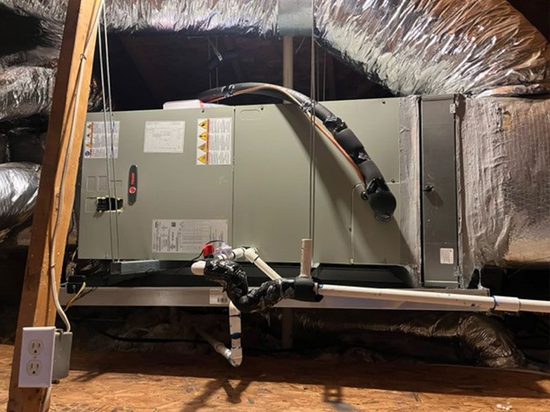 HVAC unit in an attic, with ductwork and a white drain pipe.