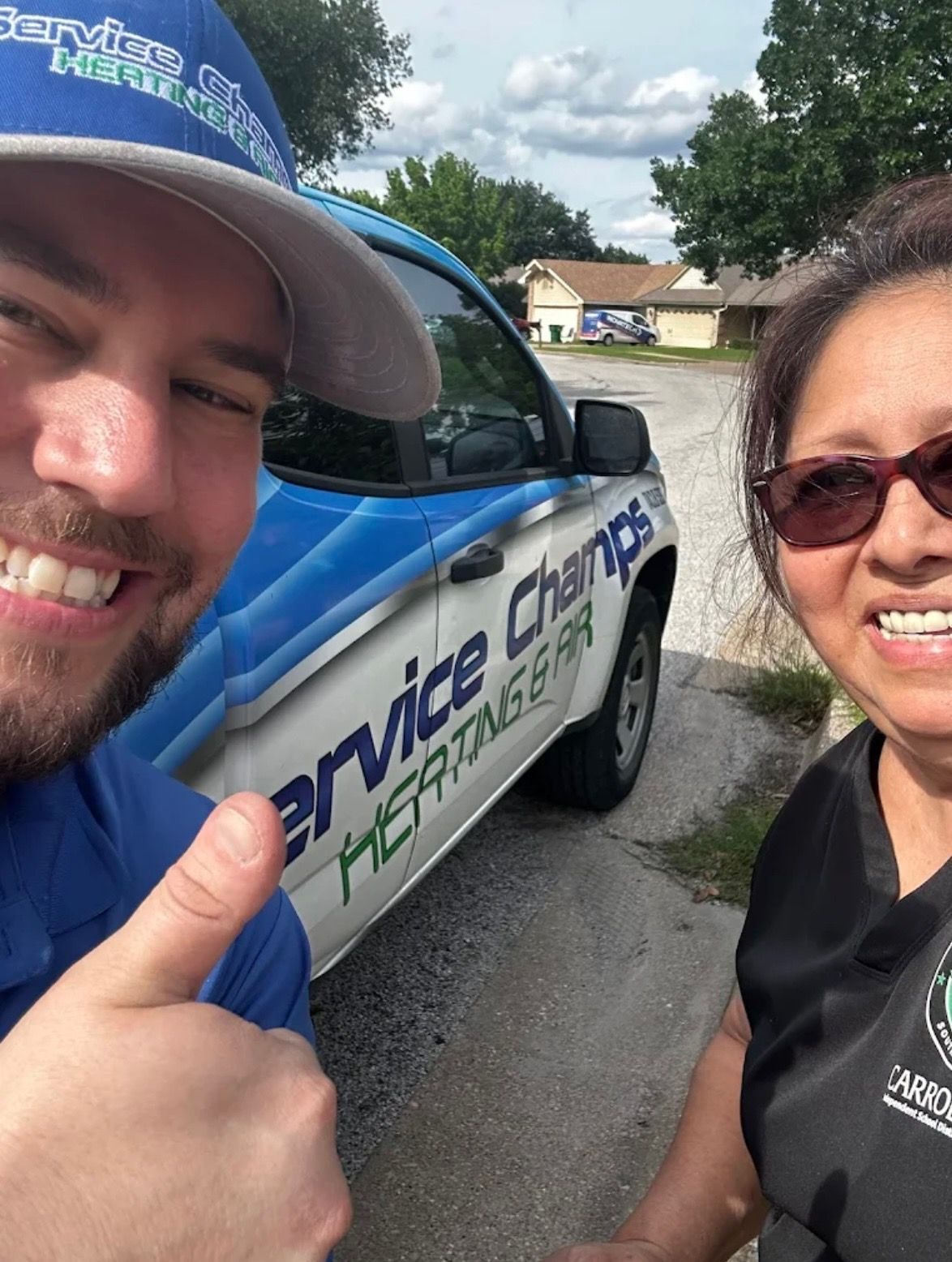 Two people smiling and posing for a selfie in front of a service car.