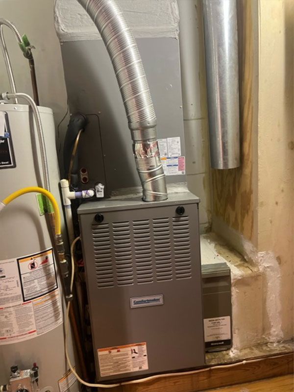A furnace and water heater in a utility room, with ductwork.