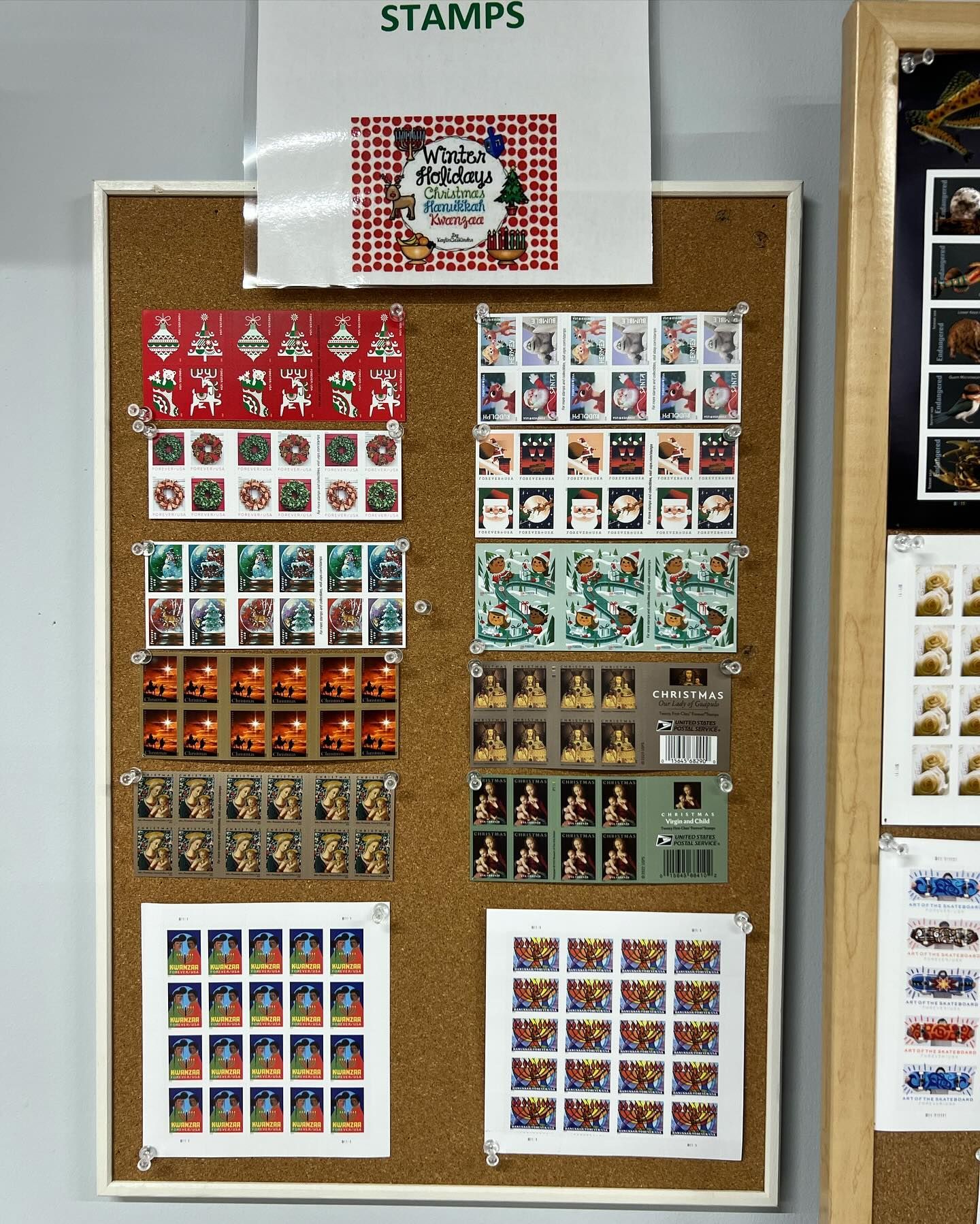 A corkboard display of various postage stamp sheets pinned under a sign reading 