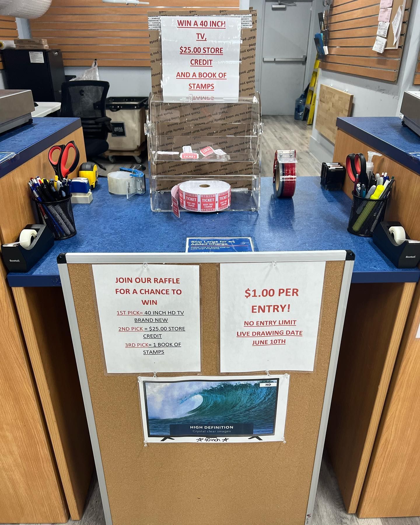 A retail service counter with signs advertising a $1 entry raffle for a TV, including various supplies and a raffle box.