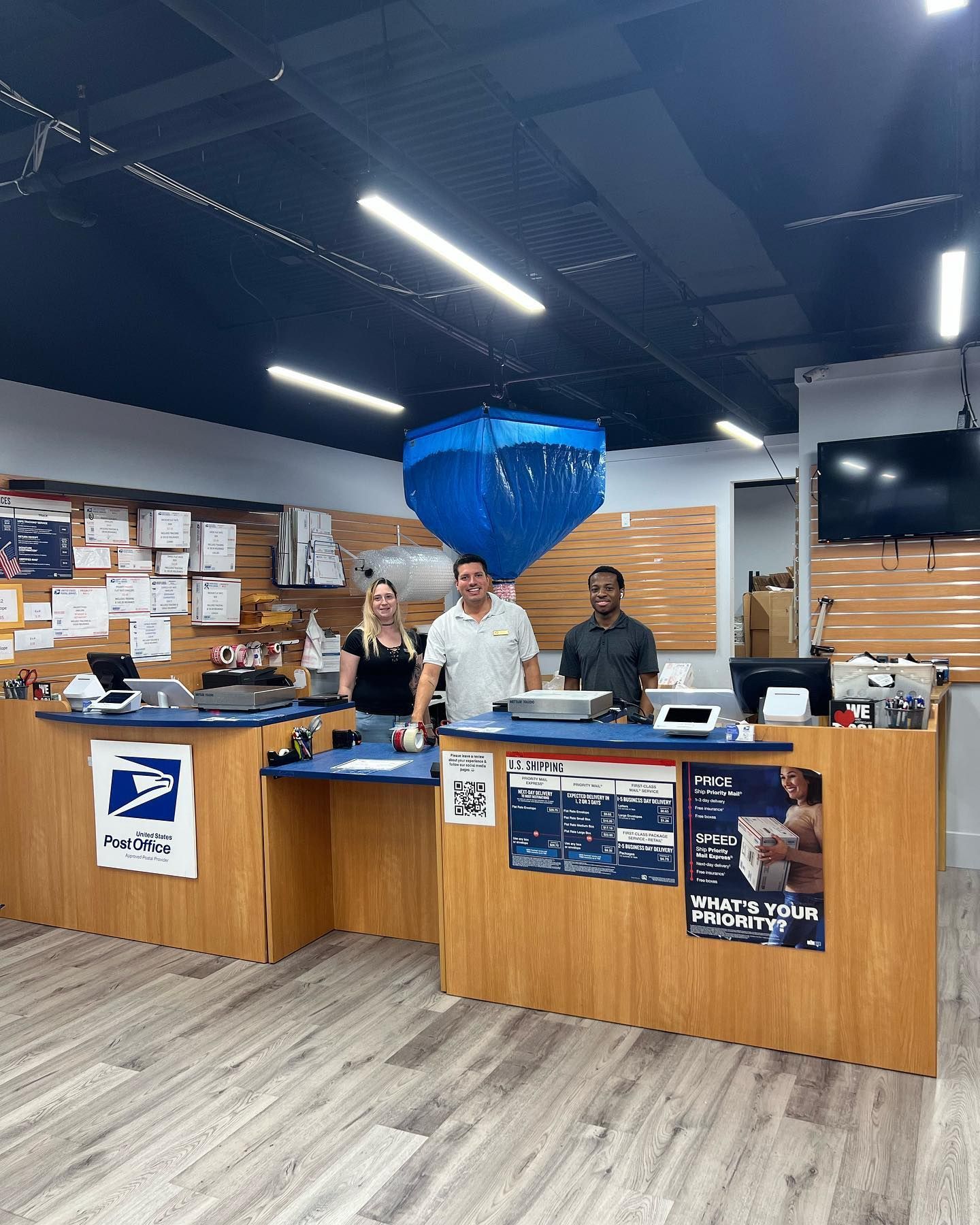 Three employees stand behind the service counters of a shipping and mailing store.