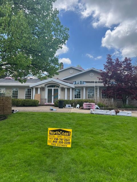 House with beige siding, a green lawn, and a NorthCoast sign in front. Overcast sky.