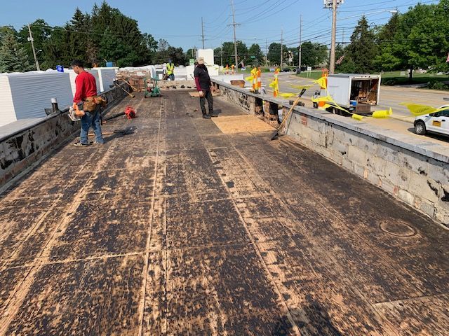 Workers on a bridge, repairing the weathered wooden deck.