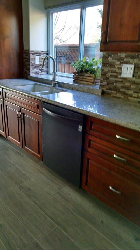 Kitchen with cabinets, sink, dishwasher, window, and tiled backsplash.