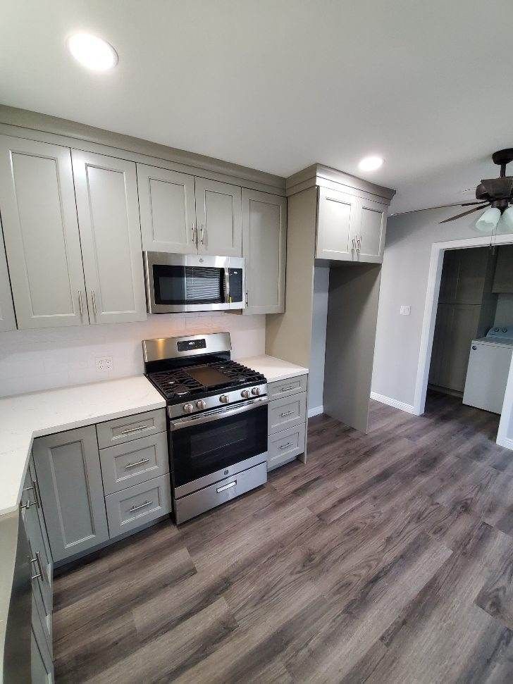 Gray kitchen with stainless steel appliances, light countertops, and wood-look flooring.