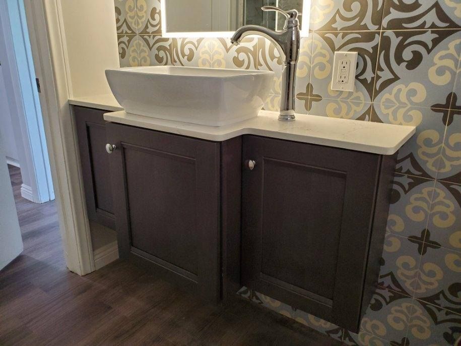 Bathroom vanity with a white rectangular sink, dark gray cabinets, and patterned tile backsplash.