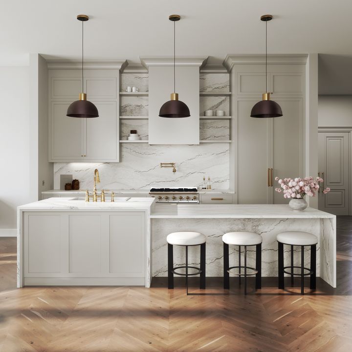 Elegant kitchen with marble countertops, gray cabinets, gold accents, and pendant lights.