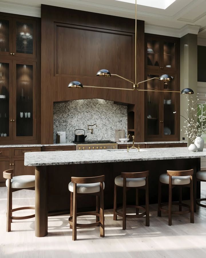 Modern kitchen with dark wood cabinetry, marble countertops, and bar stools.