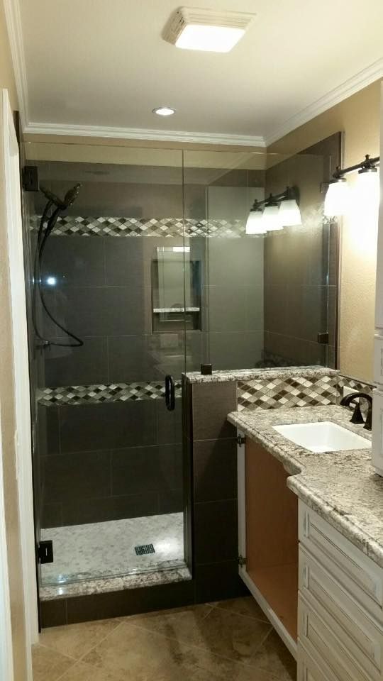 Bathroom with dark gray tile shower, glass door, vanity with white cabinets, and granite countertop.