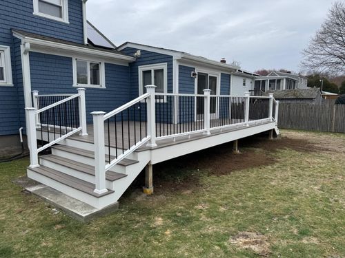Blue house with a white accessibility ramp and stairs leading to a raised deck over a grassy yard