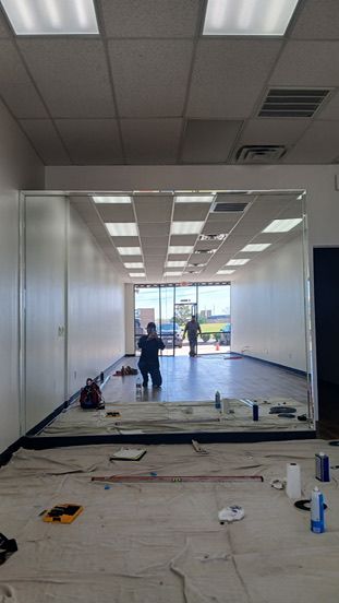 A large wall-mounted mirror reflects a brightly lit, empty retail space with an open storefront window.
