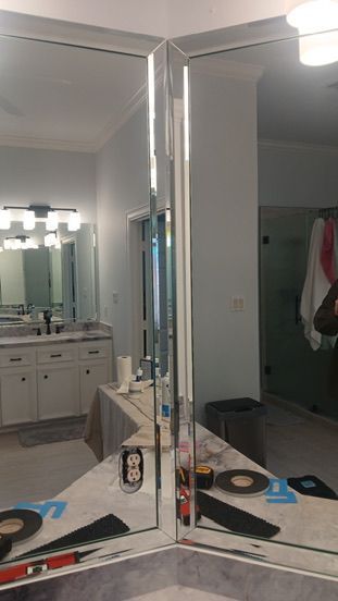 Two large, frameless rectangular mirrors mounted at a 90-degree corner in a bathroom.