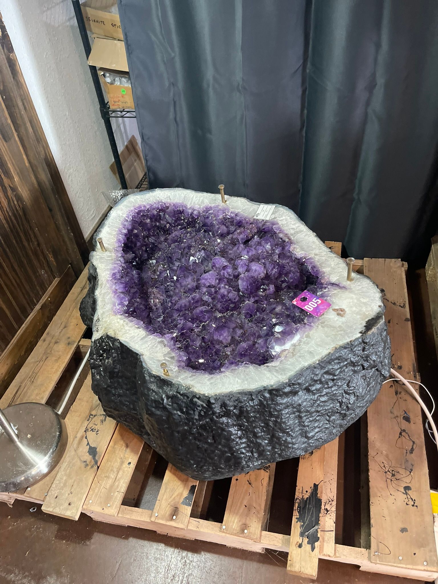 A large, deep purple amethyst geode sits on a wooden shipping pallet.