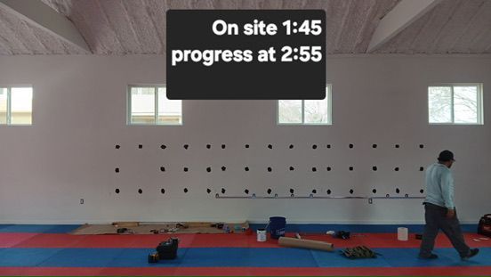 A person walks through a room with a wall marked for installation, with an overlay text reading 