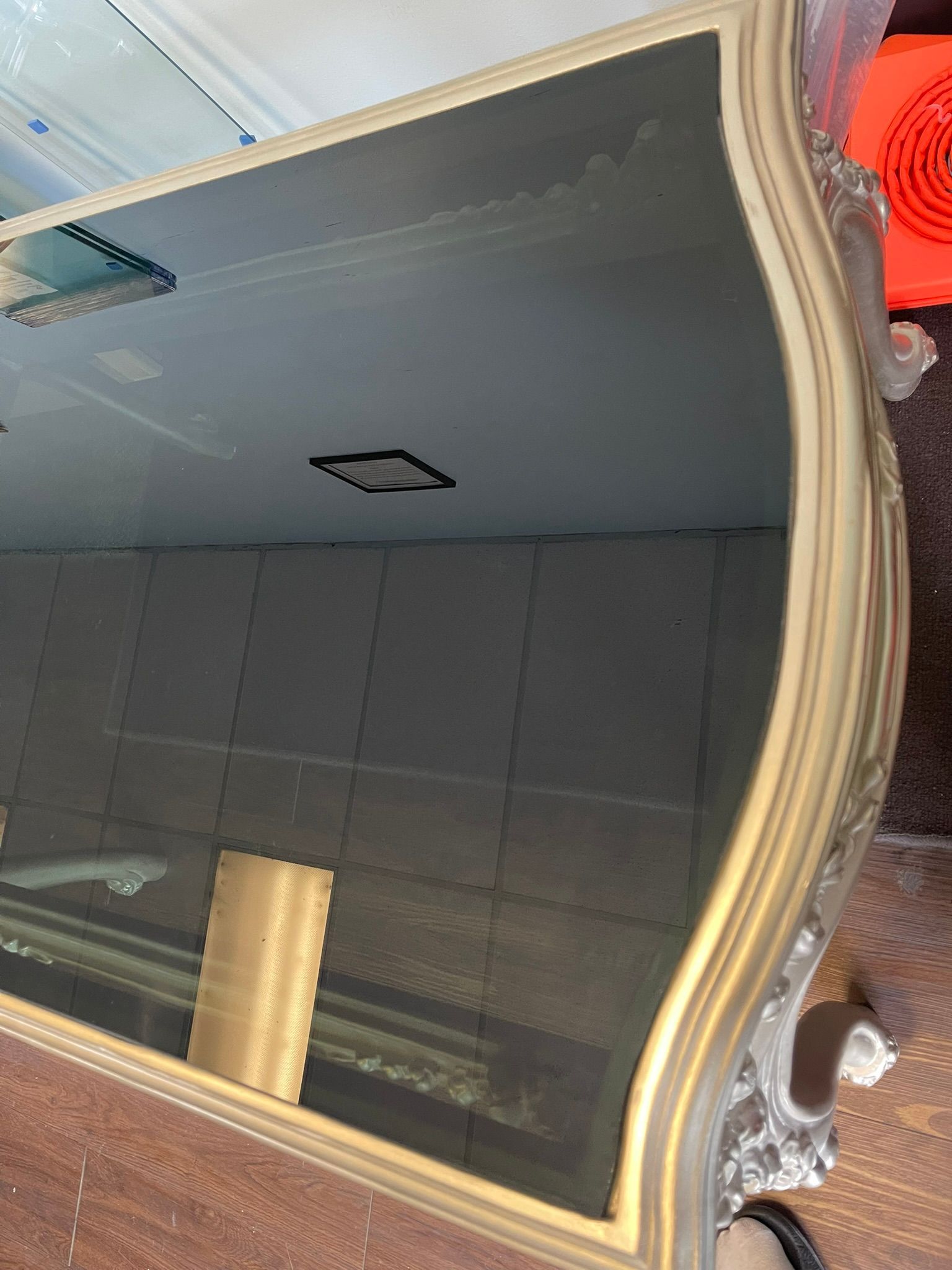 A close-up view of a dark, reflective furniture top with a light-colored, ornate, curved trim.