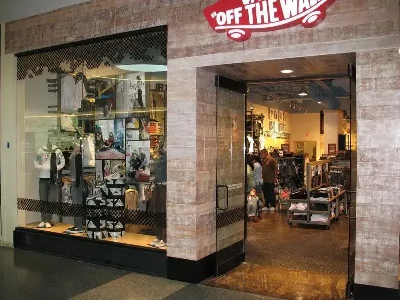 A Vans storefront entrance in a shopping mall with a brick-patterned facade and an 