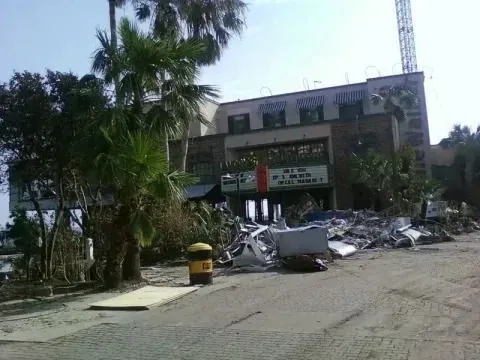 A building with a banner and a large pile of storm debris in the foreground.