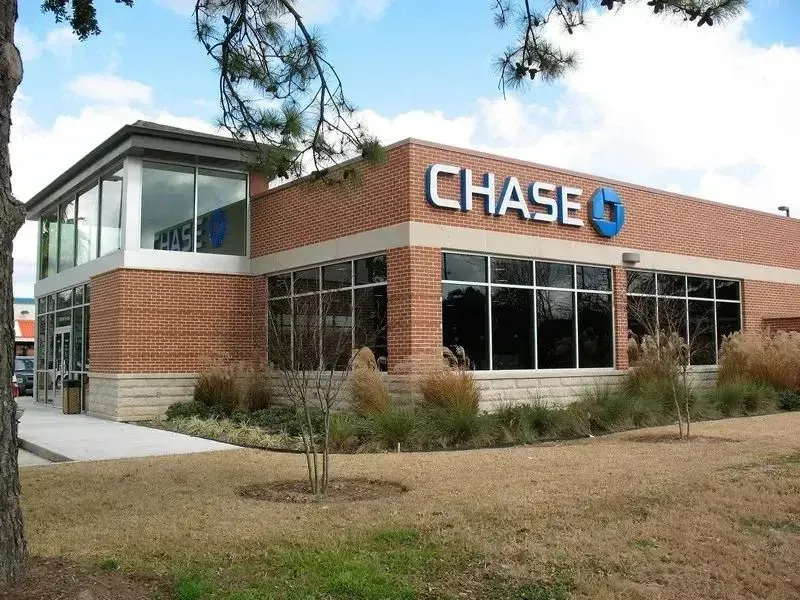 A single-story red brick Chase bank building with large windows, landscaping, and a blue Chase logo sign.