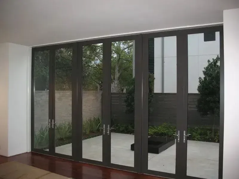 Large glass sliding doors opening to a small courtyard with stone paving and greenery
