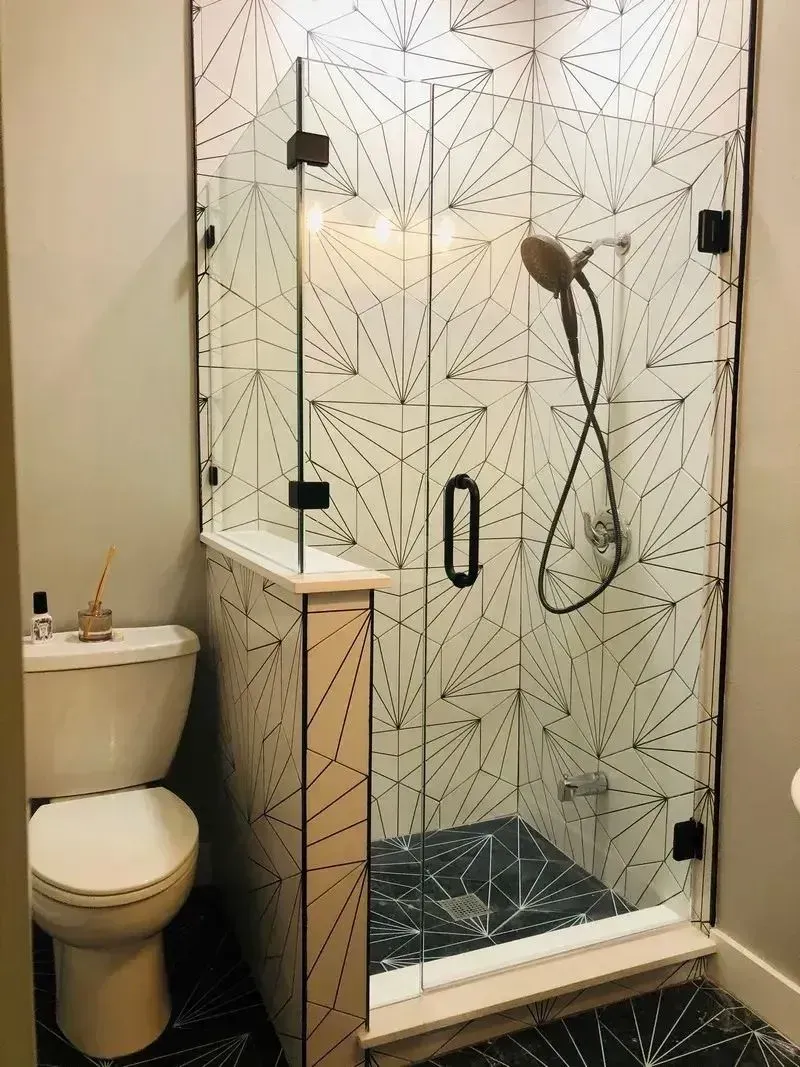 A walk-in shower with geometric starburst patterns on the glass walls and floor, located next to a white toilet.