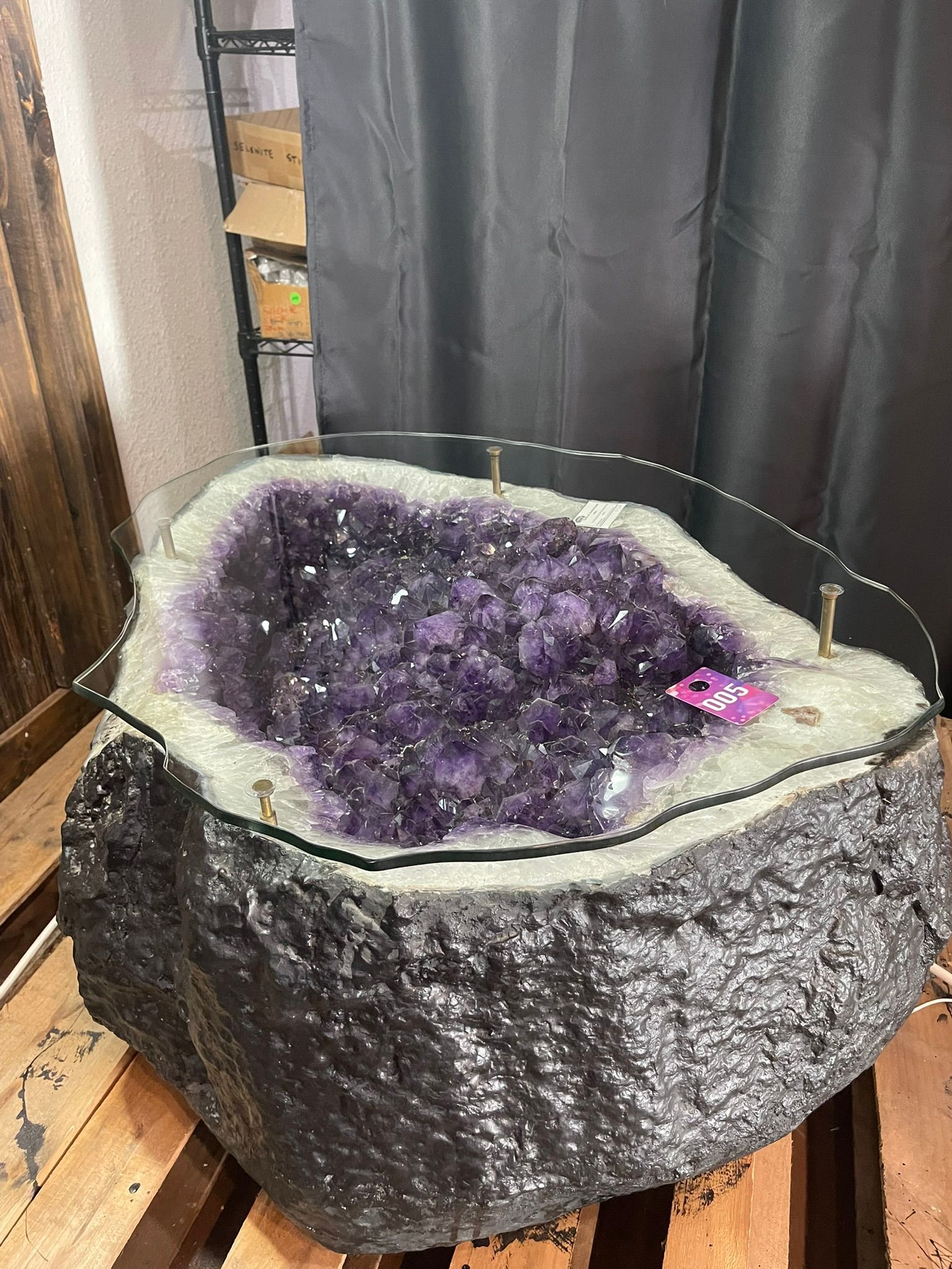 Purple crystal geode rock with white rim, displayed indoors on a wooden floor.