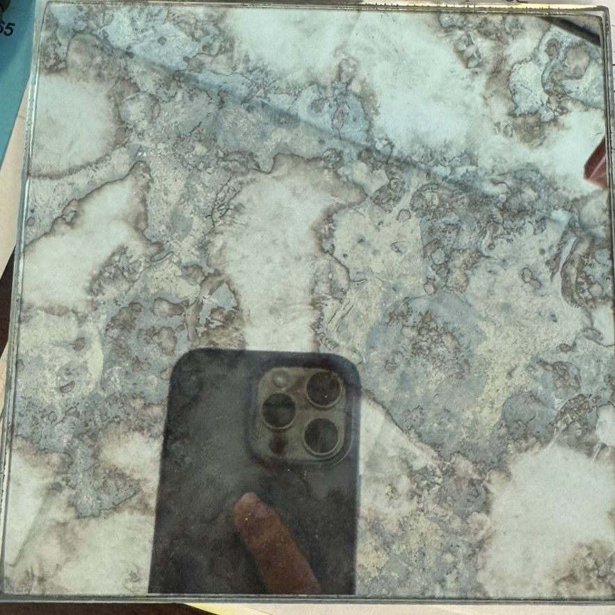 A marble-patterned tile surface reflecting a smartphone at the bottom center.
