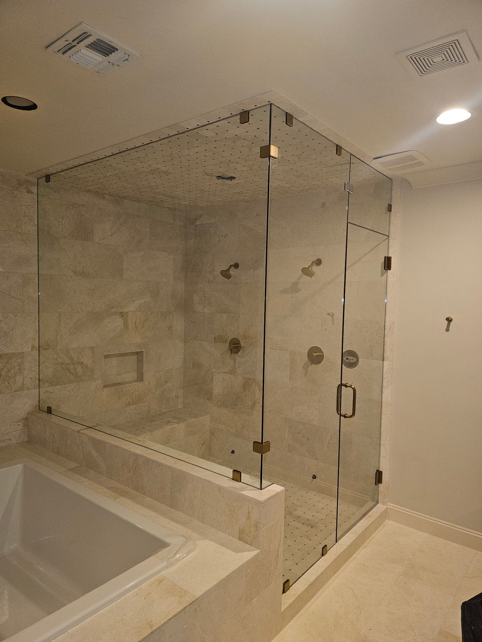 Modern bathroom with glass-enclosed shower, bathtub, and beige tile walls