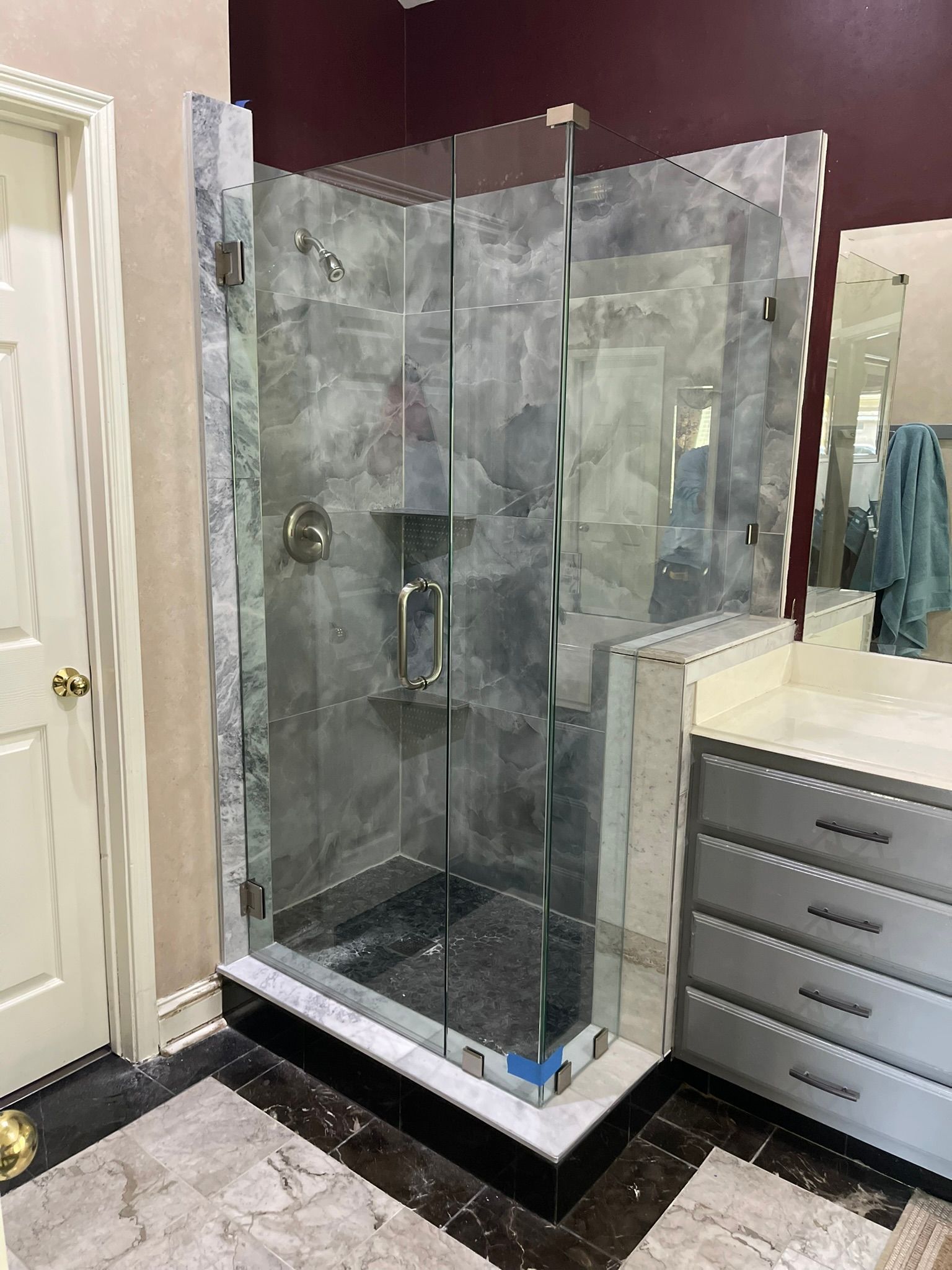 Glass walk-in shower with gray tile and chrome fixtures beside a bathroom vanity