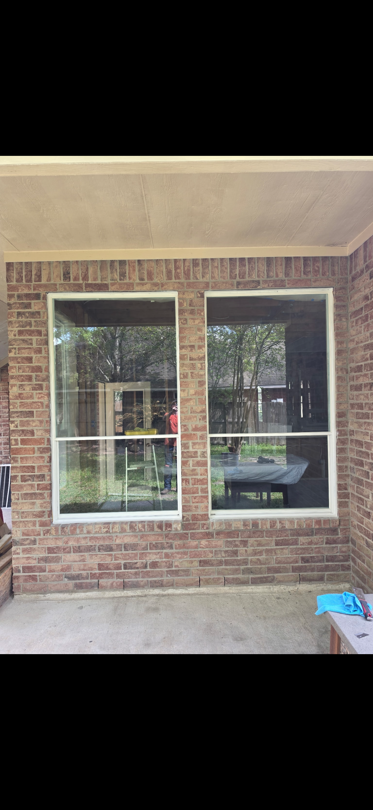 Brick house exterior with two white-trimmed windows beneath a porch roof