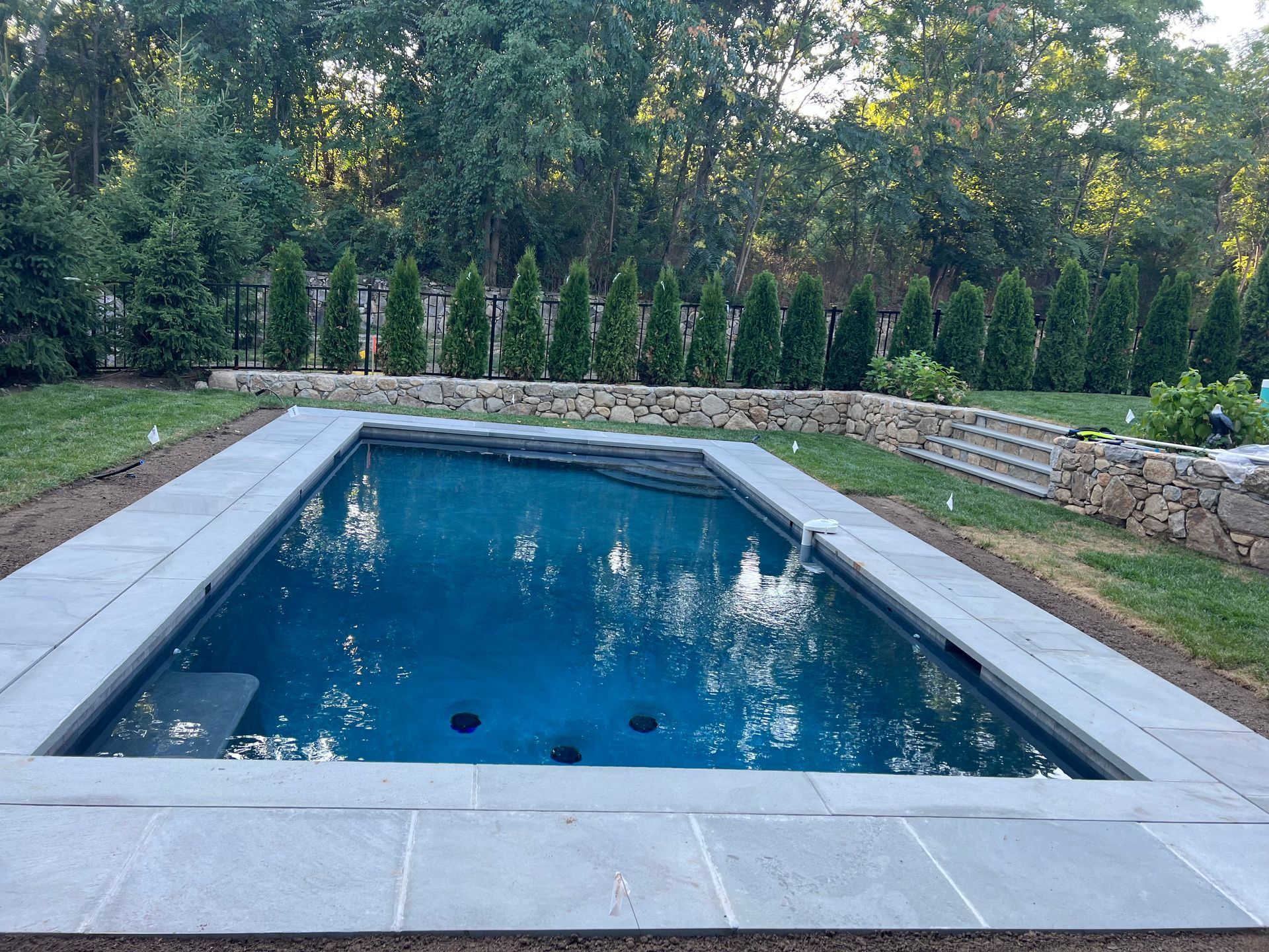 A large pool project surrounded by trees and grass.