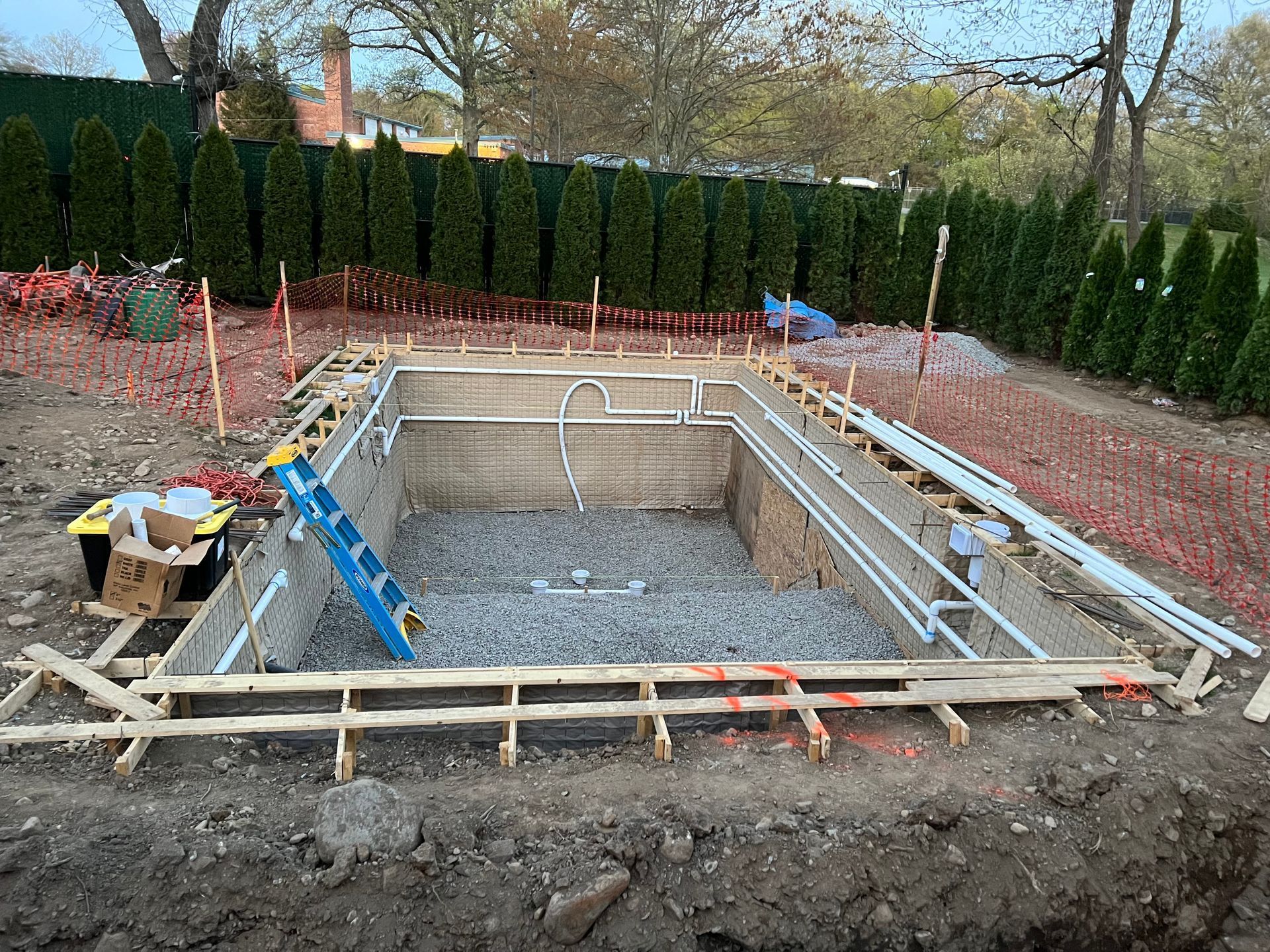 A large swimming pool installation is being built in a backyard.