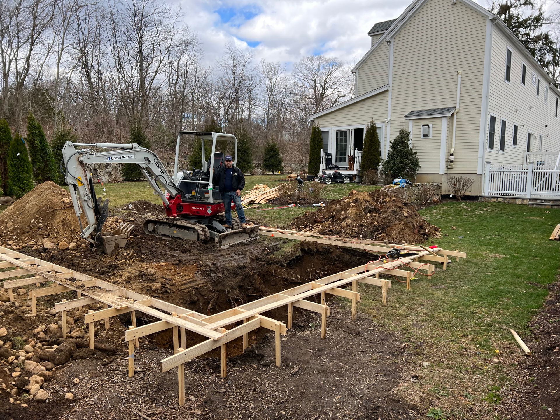 Creating a pool's foundation with Doug in front of a house.