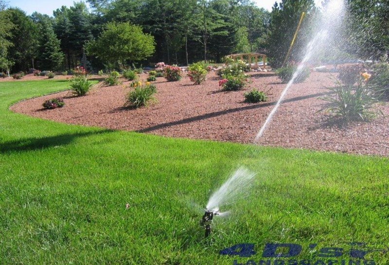 A sprinkler is spraying water on a lush green lawn.